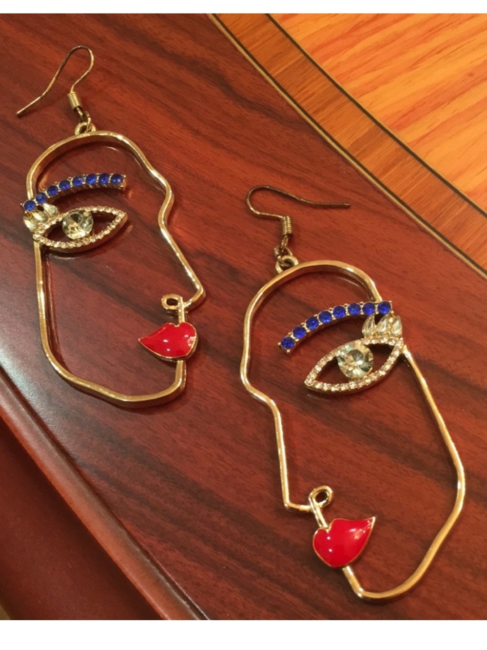 Face embellished dangling gold tone earrings